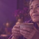 Manos de una mujer mayor sosteniendo una taza de cerámica, símbolo de envejecer con propósito